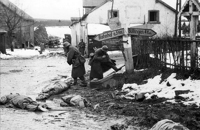 German paratroopers of Fallschirmjäger-Regiment 9 strip boots and other equipment from the bodies of killed American soldiers in Honsfeld